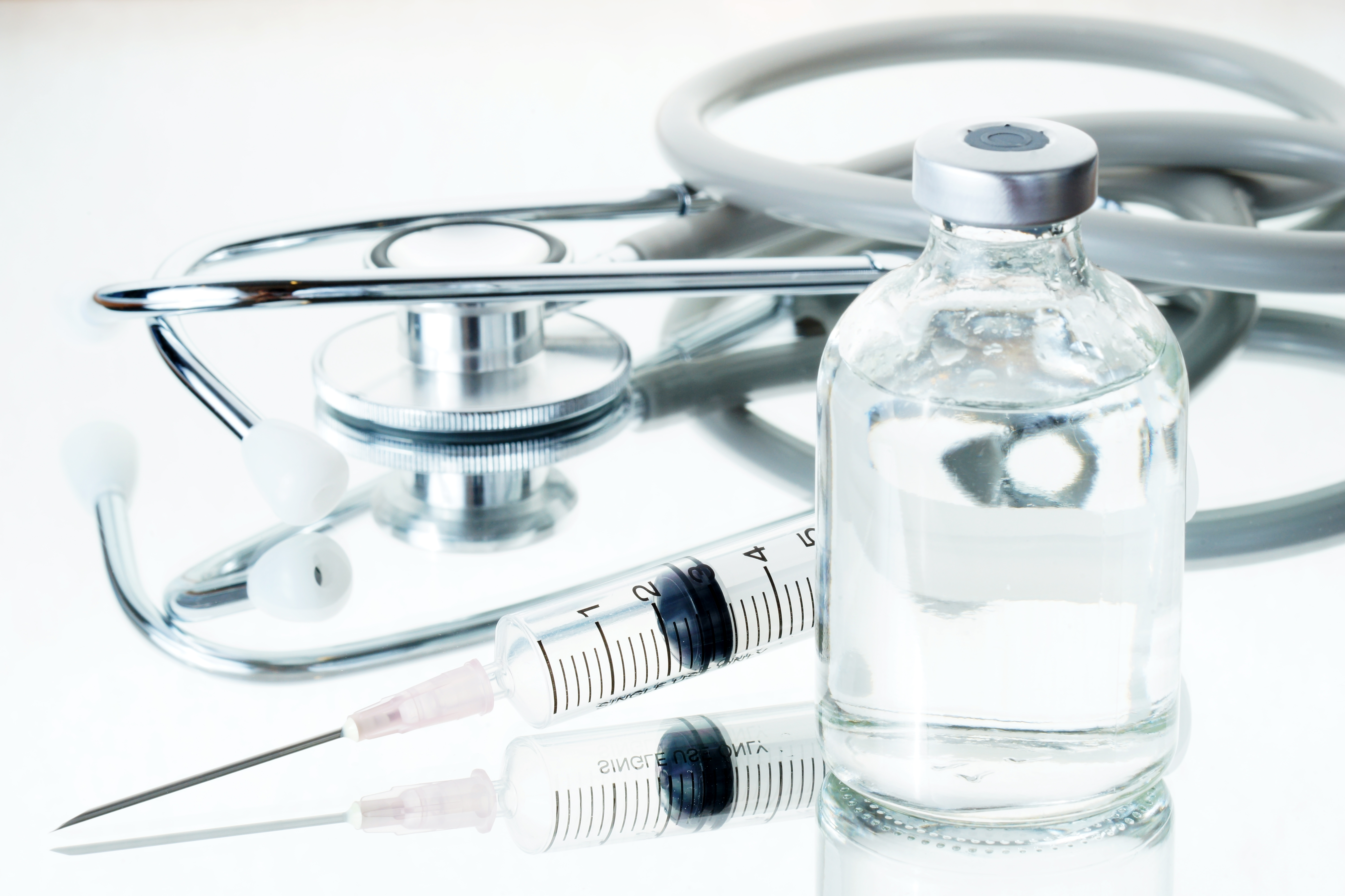 Medical ampoules, syringe and stethoscope on white background